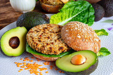 Tasty vegetarian healthy food, homemade burgers made from orange lentils legumes with green lettuce and fresh ripe avocado