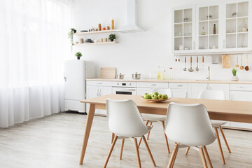 Modern kitchen interior. Wooden dining table, white chairs and furniture with utensils, empty space