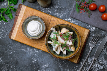 milk mushroom salted on a plate with sour cream on dark concrete table