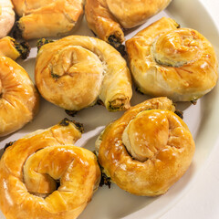 Mediterranean cuisine. Food banner with a national Greek causing with homemade pies with feta cheese and spinach on a white background. Healthy home baking pastries, close up