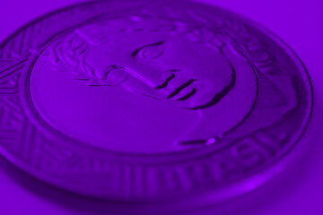 Brazilian 1 one real coin close-up. Deep violet background or wallpaper. Reverse of the coin with the Figure of the Republic. Dark purple backdrop about money, finance and banking in Brazil. Macro