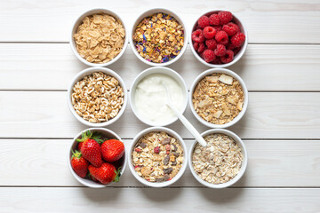 cereals, flakes, granola, berries and yogurt, various delicious ingredients for healthy breakfast in small bowls