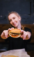 A young girl holds a burger with a meat patty in her hands.Delicious and hearty lunch.