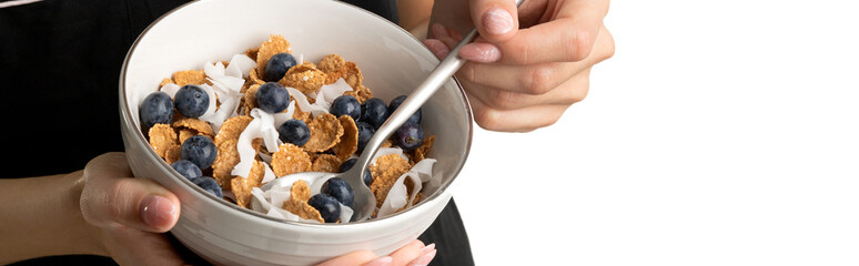 Woman in sleepwear holding bowl with whole wheat flakes, blueberry and coconut