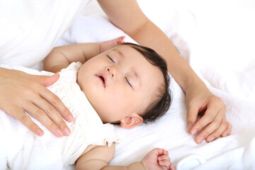 Obraz na płótnie Canvas 白背景で昼寝する赤ちゃんを見守るお母さん。育児、母性、愛情イメージ