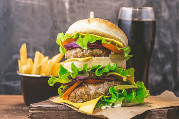Big burger with meat cutlet and fresh drink on a wooden background. Junk food concept.