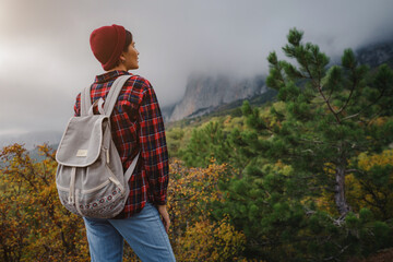 Happy young woman with backpack exploring misty mountains.