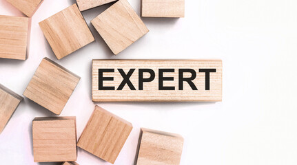 On a light background, wooden cubes and a wooden block with the text EXPERT. View from above