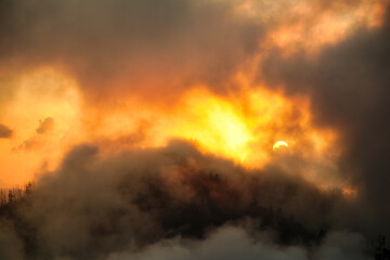 Fototapeta na wymiar Fiery burst of sunlight break in the dark clouds - beautiful spectacular sunset
