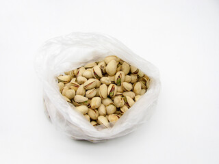 fried pistachios in a transparent bag on a white background.
