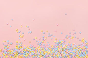 Colorful tiny balls confetti exploding on pastel pink background