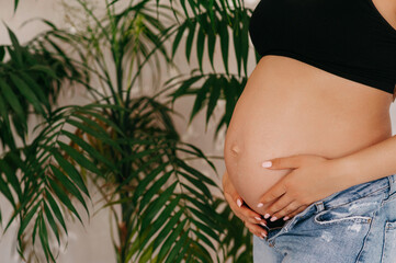 Cute pregnant belly.  Side view of a young pregnant woman hugging her naked belly with her hands....