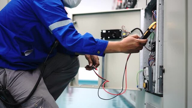 An industrial electrician is inspecting the electrical control cabinet, industrial operation concept and technology.