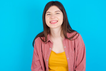 Fototapeta premium young beautiful Caucasian woman wearing pink jacket over blue wall with happy and funny face smiling and showing tongue.