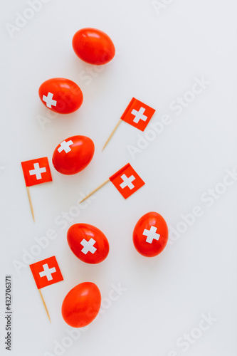 Celebrating Swiss National Holiday on August 1st with traditional eggs colored like swiss flag. Red eggs and swiss flags scattered around.