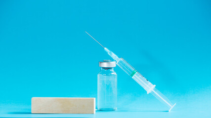 Medical ampoule and syringe with the empty wooden block with empty place for text on blue