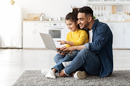 Happy Arab Man With His Little Daughter Using Laptop Together At Home