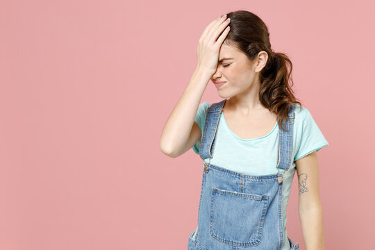 Young ashamed mistaken confused caucasian woman in denim clothes blue t-shirt put hand on face facepalm epic fail gesture isolated on pastel pink background studio portrait People lifestyle concept.