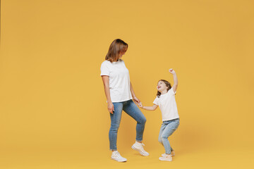 Fototapeta na wymiar Full body length happy woman in basic white t-shirt have fun child baby girl 5-6 years old hold hands dance Mom little kid daughter isolated on yellow color background studio Mother's Day love family