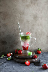 Strawberry matcha latte in a transparent double glass cup. Cold drink. Healthy eating. Raw cuisine.