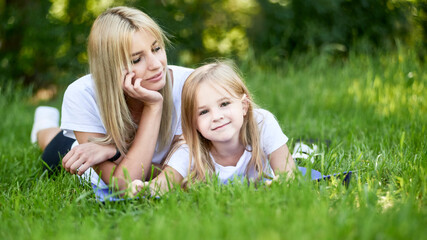 Fototapeta premium Mid adult mothers are resting with her daughter on a summer day outdoors.