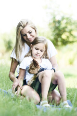 Fototapeta premium Mid adult mothers are resting with her daughter on a summer day outdoors.