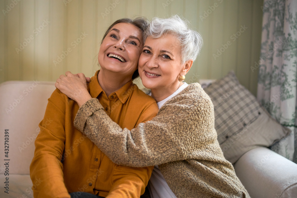 Wall mural friendship, family and relationships concept. happy carefree mature sisters bonding, sitting on comf