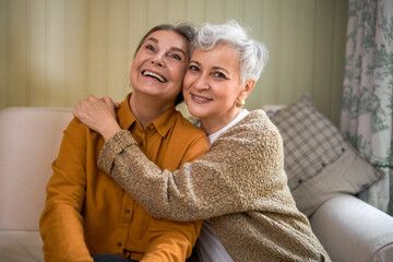 Friendship, family and relationships concept. Happy carefree mature sisters bonding, sitting on...