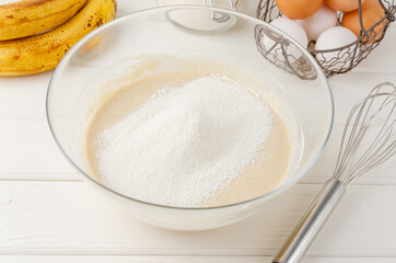 Cooking oatmeal pancakes with bananas. Eggs, buttermilk, sugar, vanilla, oatmeal and flour in a bowl on a white wooden background. Recipe step by step.
