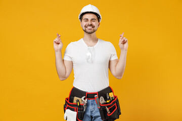 Young employee handyman man in protective helmet hardhat wait special moment keep fingers cross...