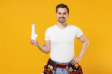 Young smiling confident employee handyman man in white t-shirt hold siphon plumbing stand akimbo isolated on yellow background Instruments accessories renovation apartment room Repair home concept