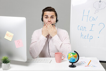 Employee shocked operator business man in set microphone headset for helpline assistance sit work...