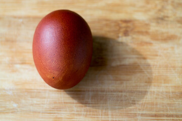 Multicolored dyed Easter egg with shadows. Easter. Brown egg on a wooden board close-up.