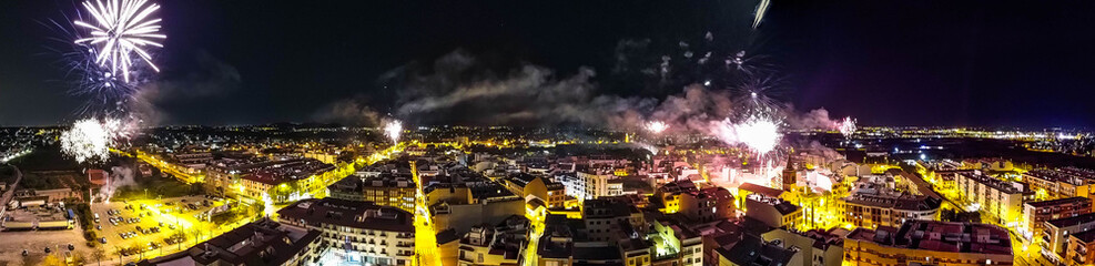 Panoramica sobre pueblo valenciano lanzando cohetes en fiestas de Fallas. Fotografia tomada con drone - obrazy, fototapety, plakaty