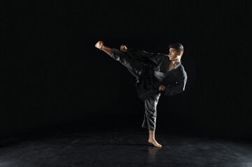 Male karateka, fighter in black kimono, training