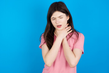 young beautiful Caucasian woman wearing pink T-shirt over blue wall shouting suffocate because...
