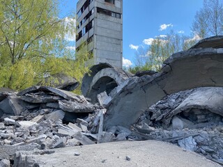 Ruined abandoned factory, concrete texture, trees among concrete and cement on a background of sky with clouds