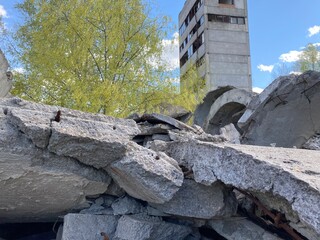 Ruined abandoned factory, concrete texture, trees among concrete and cement on a background of sky with clouds