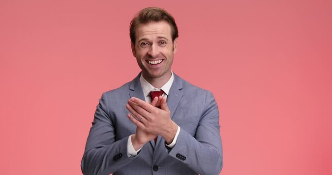 enthusiastic businessman hearing good news, feeling joyful and clapping, pointing fingers and making thumbs up gesture on pink background in studio