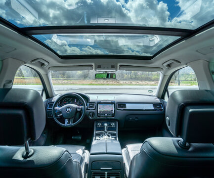 Panoramic view inside car - double sunroof hatch with tinted glass. Sliding panoramic sunroof and luxurious leather seats. Close up photo with bright blue sky seen through sunroof.