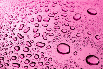 Abstract background with water drops on a pink surface with metallic shine