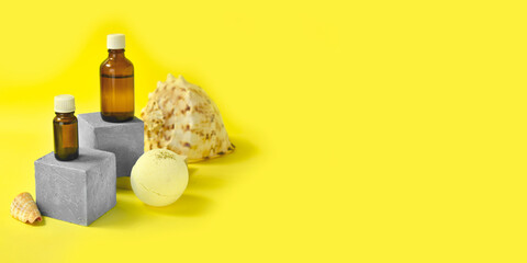 Mock up minimalist natural bath cosmetic concept with body care oil bottle, spa bomb, seashells on pedestals on yellow background. Spa aromatherapy treatment. Sea resort. Sunscreen beauty products.
