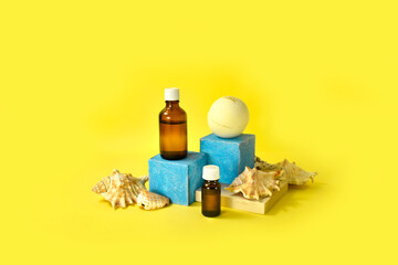 Bath aromathrerapy treatment with cosmetic bottles, spa bomb and sea shells on yellow background. Spa natural skin care products on podiums for presentation, branding. Summertime resort concept.