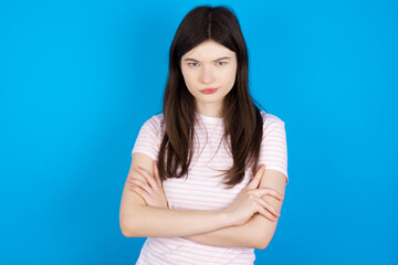 young beautiful Caucasian woman wearing stripped T-shirt over blue wall Pointing down with fingers showing advertisement, surprised face and open mouth
