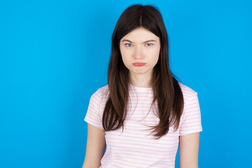 young beautiful Caucasian woman wearing stripped T-shirt over blue wall depressed and worry for distress, crying angry and afraid. Sad expression.