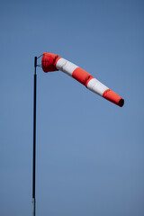 Closeup of striped windsock waiving in the wind against bright blue sky.
