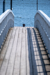 Old wooden pier with white wooden railings against the blue sea.