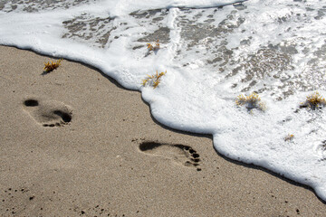 Surf washing away footprints in sand