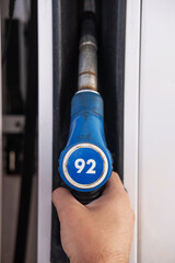 A pistol for refueling with gasoline at a gas station. Blue gas pump at the gas station. On the pistol, the inscription means 92 gasoline.