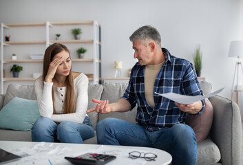 Mature couple having heated discussion about family budget, in trouble paying all bills, checking...